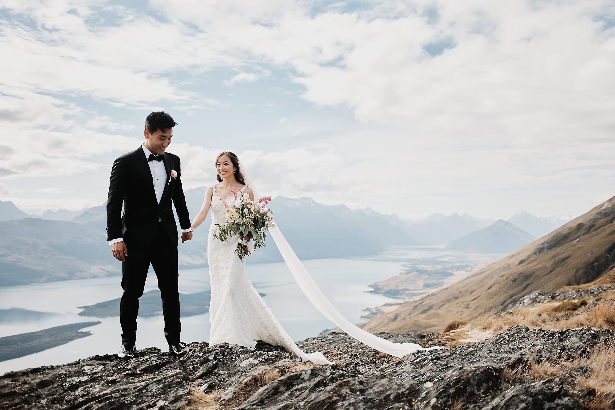 クイーンズタウン　ニュージーランド　ウェディング　前撮り　挙式　結婚式　フォトグラファー | ワナカ湖を見下ろす山の上でクイーンズタウンのヘリウェディングを楽しむ新郎新婦。